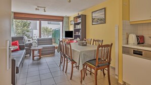 Un comedor con mesa y sillas, un sofá, una estantería y una cocina equipada.