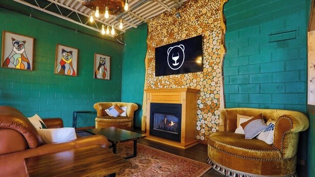 Un espacio lounge acogedor con sofás de cuero, una chimenea y una pared decorada con mosaicos circulares.