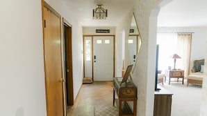 Un pasillo con suelo de madera, un espejo, una maleta y una puerta con el rótulo 'Behr Brewing'.