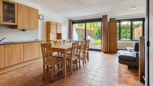 A spacious kitchen with wooden cabinets, a dining table with chairs, and a large window with curtains. - 3 bedroom accommodation in Nieuwpoort (Nieuwpoort)