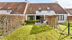 A residential building with a tiled roof, a front garden, and a patio area with outdoor furniture. - 3 bedroom accommodation in Nieuwpoort (Nieuwpoort)
