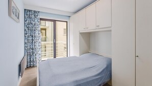 A bedroom with a bed, a wardrobe, a radiator, and a window with curtains.