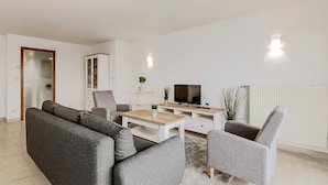 A modern living room with a grey sofa, a wooden coffee table, a TV, and a cabinet.