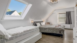A bedroom with a skylight, two beds, a radiator, and a window with curtains. - Villa in Oostduinkerke (Oostduinkerke)