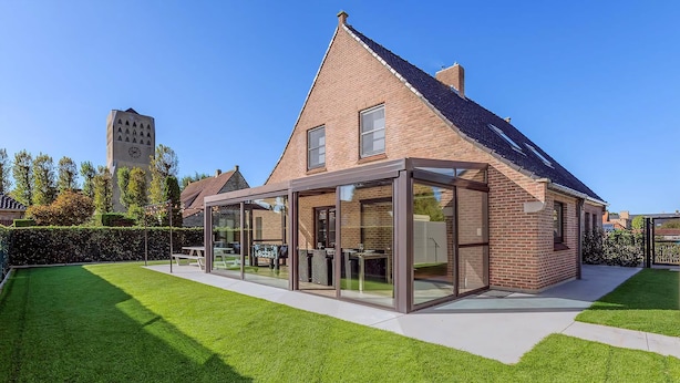 A modern house with a glass extension, a brick exterior, and a well-maintained lawn. - Villa in Oostduinkerke (Oostduinkerke)
