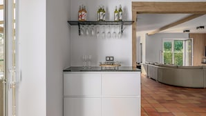 A modern kitchen with a built-in island, wine bottles on a shelf, and hanging glasses. - Villa in Oostduinkerke (Oostduinkerke)