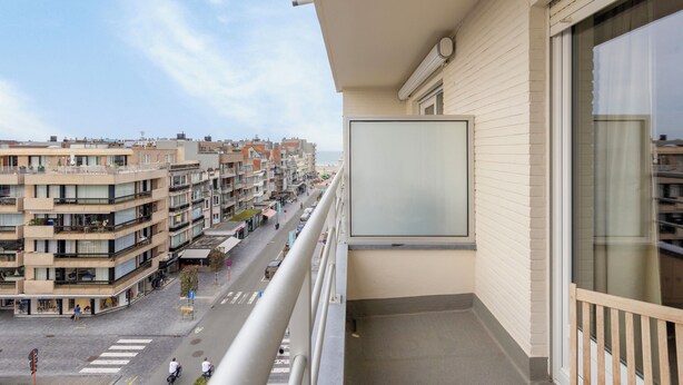 A balcony with a view of a city street, buildings, and a clear sky. - 2 bedroom accommodation in Koksijde (Koksijde)