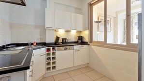 A compact kitchen with white cabinets, a black countertop, and a window with a view. - 2 bedroom accommodation in Koksijde (Koksijde)