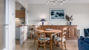 A dining area with a round table and six chairs, a wooden cabinet, a lamp, and a framed picture on the wall.