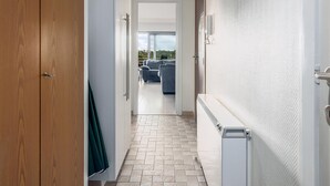 A hallway with a wooden door, a radiator, and a view of a balcony with a sofa.