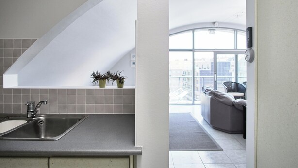 A modern kitchen with a built-in sink and a view of a balcony with a sofa and a cityscape.
