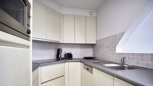 A compact kitchen with a built-in oven, a coffee maker, and a sink.