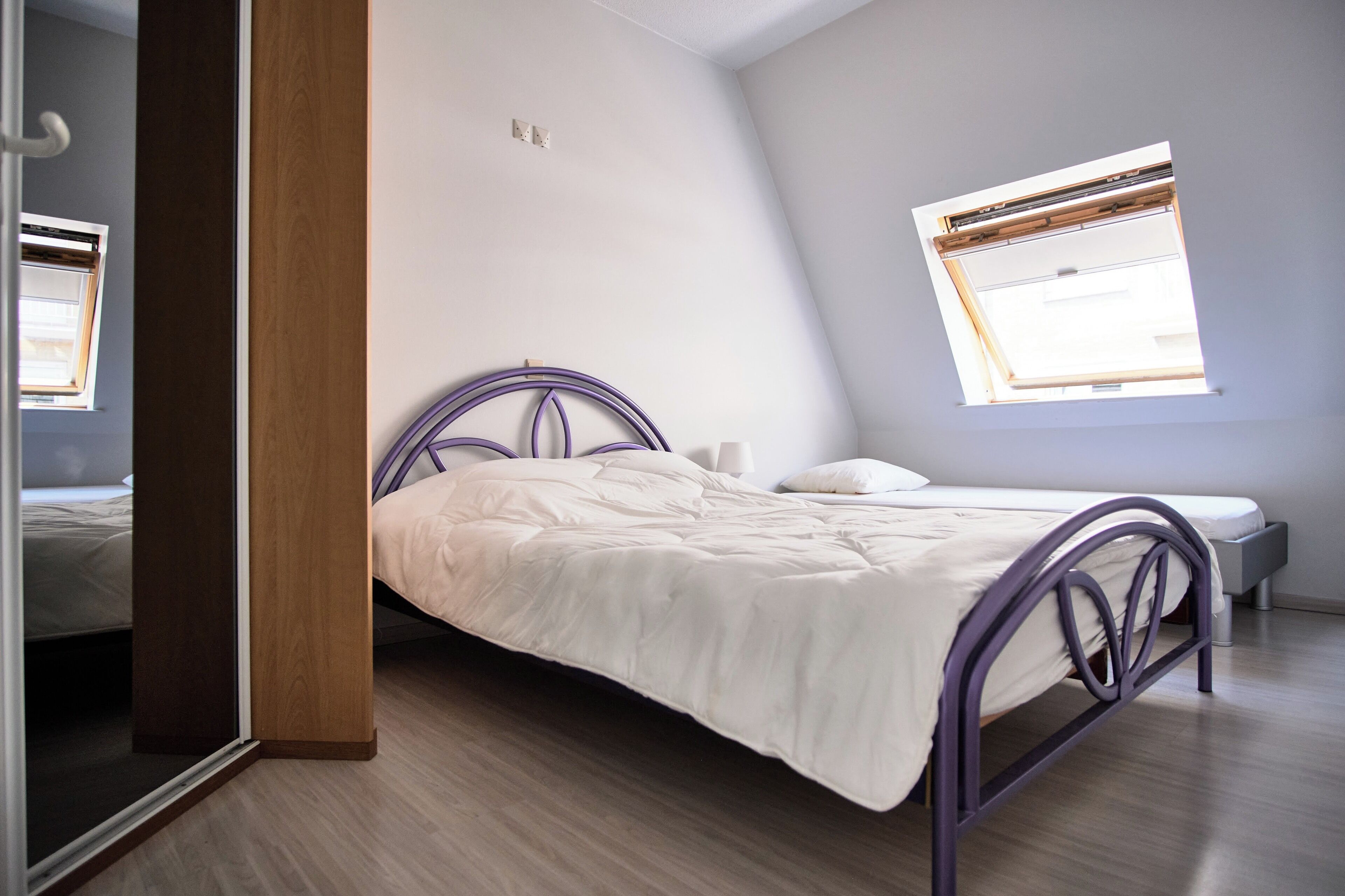 Ein Schlafzimmer mit Bett, Nachttisch, Fenster mit Jalousien und einer Tür.