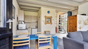A compact living space with a dining area, kitchenette, and a staircase leading to an upper level.