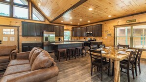 A spacious kitchen with dark wooden cabinets, a stainless steel refrigerator, and a large island with stools.
