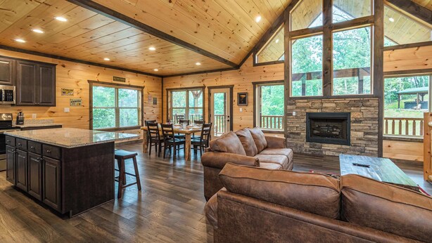 A spacious cabin interior with a large dining area, a cozy living room with a fireplace, and a kitchen with a granite countertop.