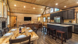 A spacious kitchen with wooden cabinets, a large island, and a dining area with a long table set for four.