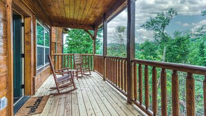A wooden porch with a view of a forest.