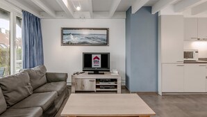 A modern living room with a grey sofa, a wooden coffee table, a flat-screen TV, and a framed picture on the wall. - 3 bedroom accommodation in Nieuwpoort (Nieuwpoort)