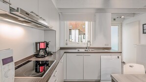 A modern kitchen with white cabinets, a built-in oven, a coffee maker, and a dishwasher. - 3 bedroom accommodation in Nieuwpoort (Nieuwpoort)