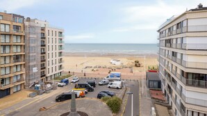 A coastal view with buildings, a beach, and parked vehicles. - 2 bedroom accommodation in Koksijde (Koksijde)