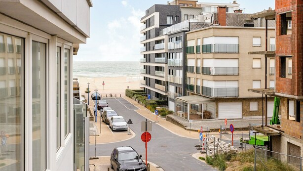 Un quartier résidentiel en bord de mer, avec des bâtiments modernes, une plage en arrière-plan et un ciel dégagé.