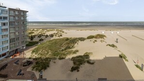 A beachside view with a building, sandy dunes, and a clear sky. - 2 bedroom accommodation in Oostduinkerke (Oostduinkerke)