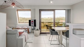 A modern kitchen with a dining area, a sofa, and a TV displaying 'ERA Real Estate Servim'. - 2 bedroom accommodation in Oostduinkerke (Oostduinkerke)