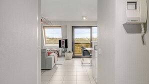 A modern living room with a sofa, TV, and a dining area with a chair and table. - 2 bedroom accommodation in Oostduinkerke (Oostduinkerke)