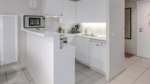 A modern kitchen with white cabinetry, a microwave, a coffee maker, and a sink. - 2 bedroom accommodation in Oostduinkerke (Oostduinkerke)