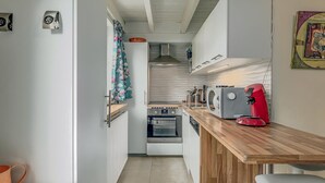 A compact kitchen with a wooden countertop, a red coffee maker, and a white oven.