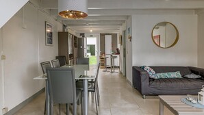 A modern living room with a dining area, a sofa, and a large mirror.