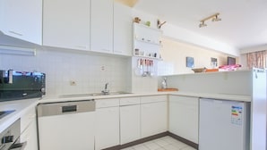 Une cuisine moderne avec des meubles blancs, un lave-vaisselle, un réfrigérateur et un four à micro-ondes.