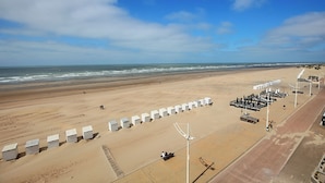 Une plage avec des structures blanches, une promenade dallée et une zone sablonneuse.