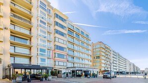 A multi-story hotel with balconies, a covered outdoor seating area, and a clear sky. - 3 bedroom accommodation in Oostduinkerke (Oostduinkerke)