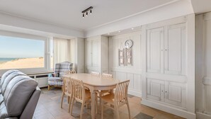 A dining area with a table and chairs, a view of the beach, and a clock on the wall. - 3 bedroom accommodation in Oostduinkerke (Oostduinkerke)