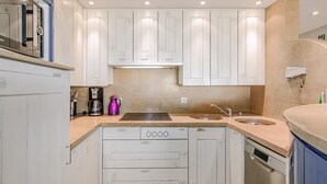 A compact kitchen with white cabinets, a built-in oven, a sink, and a dishwasher. - 3 bedroom accommodation in Oostduinkerke (Oostduinkerke)