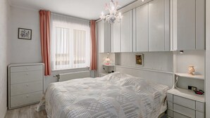 Ein Schlafzimmer mit Bett, Schminktisch, Nachttisch, Lampe und einer Chandelier.