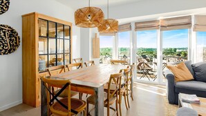 Un vaste espace dédié à la salle à manger, avec une table et des chaises en bois, un canapé et une vue sur l’extérieur.