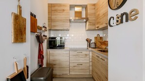 Une cuisine moderne avec des meubles en bois, un four en acier inoxydable et une horloge au mur.