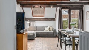 Una sala de estar acogedora con un sofá gris, una mesa de madera preparada para comer y un radiador.