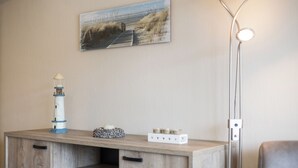 A wooden desk with a lighthouse model, a candle holder, and a small box of candles. A painting of a beach scene hangs above the desk. - 2 bedroom accommodation in Koksijde (Koksijde)