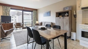 A modern living room with a dining area, a television, and a kitchen. - 2 bedroom accommodation in Koksijde (Koksijde)