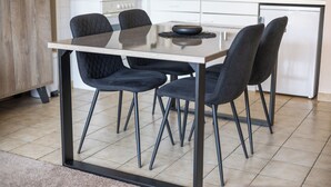 A modern kitchen with a dining table, four chairs, and a microwave. - 2 bedroom accommodation in Koksijde (Koksijde)