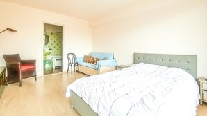 Ein Schlafzimmer mit einem großen Bett, einem Sessel, einer Couch und einem kleinen Tisch.
