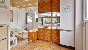 Eine kleine Küche mit Holzausbau, einem K ühlschrank und einem Essbereich mit einer Bank und einem Tisch.