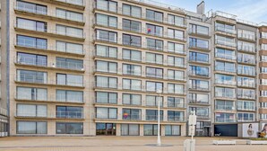 Un edificio residencial de varios pisos con balcones, ventanas amplias y fachada plana.
