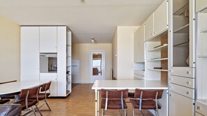 Una cocina moderna con armarios blancos, una mesa de comedor con sillas y vistas al área de comedor contigua.