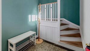 Una escalera con barandillas blancas y escalones de madera, un banco blanco y una pequeña mesa con una cesta.