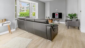 Una sala de estar moderna con un sofá gris, una mesita, un televisor y una planta.